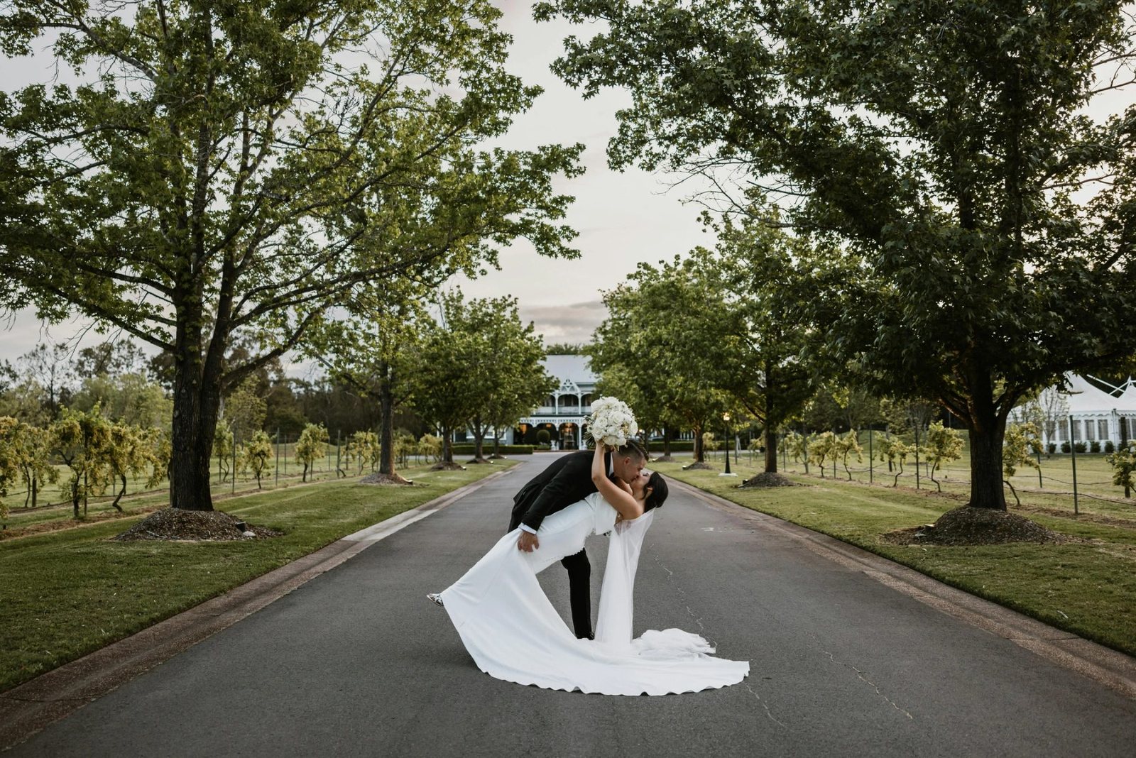 A groom dipping the bride on the driveway at dusk