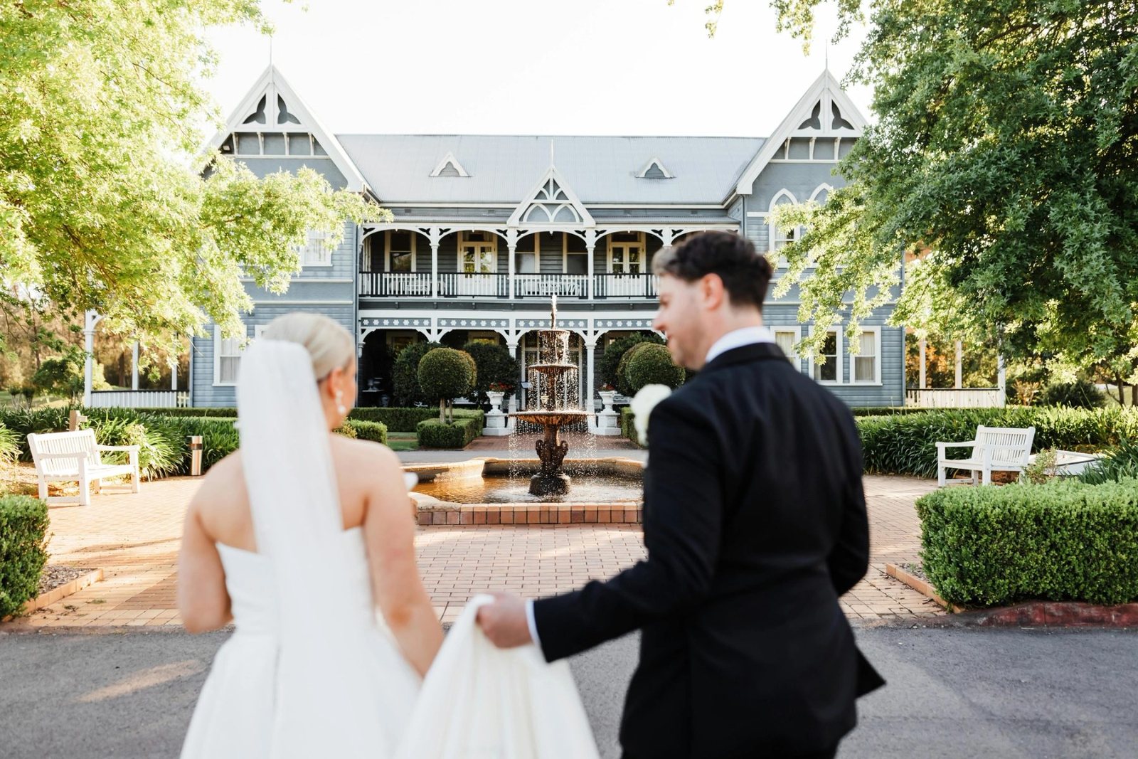 A couple walking hand in hand toward the Convent and the fountain