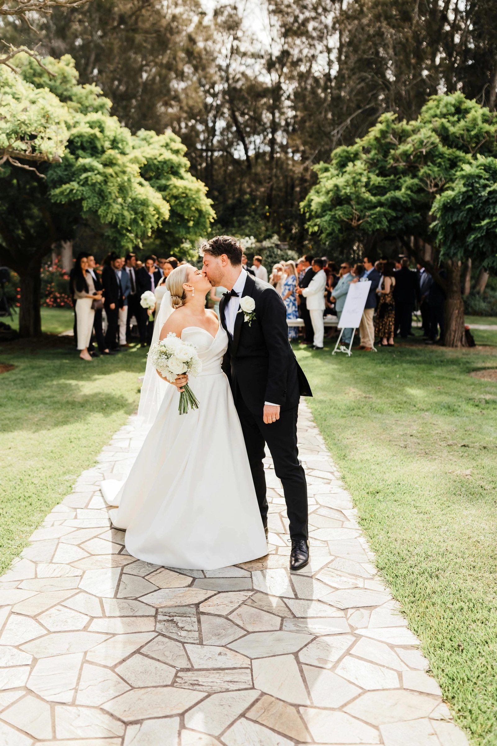 A couple walking the garden path with guests following