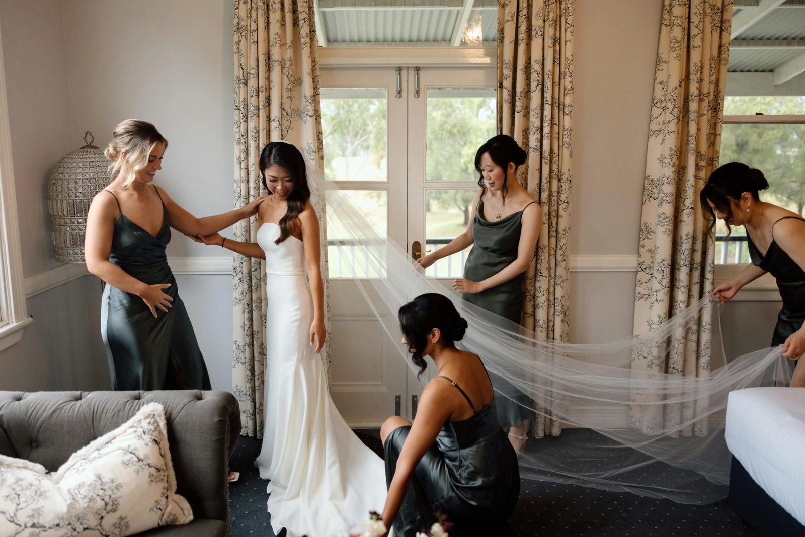 A bride getting ready with two attendants by a window